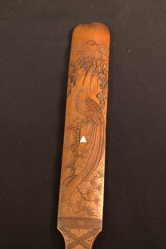 Paddleboard A wooden paddleboard with an image of a bird beneath a waterfall and the sun.