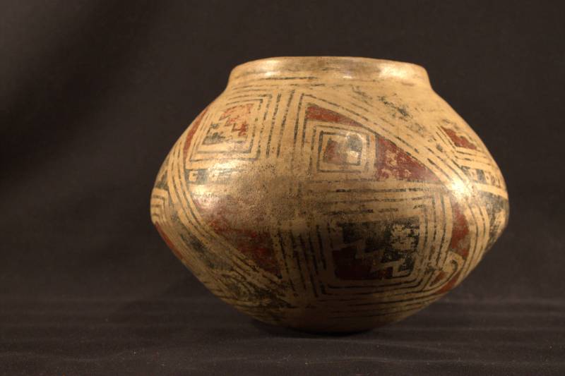 Jar Jar decorated with a stepped triangle geometric design. The red and black paint making up the design is heavily worn.