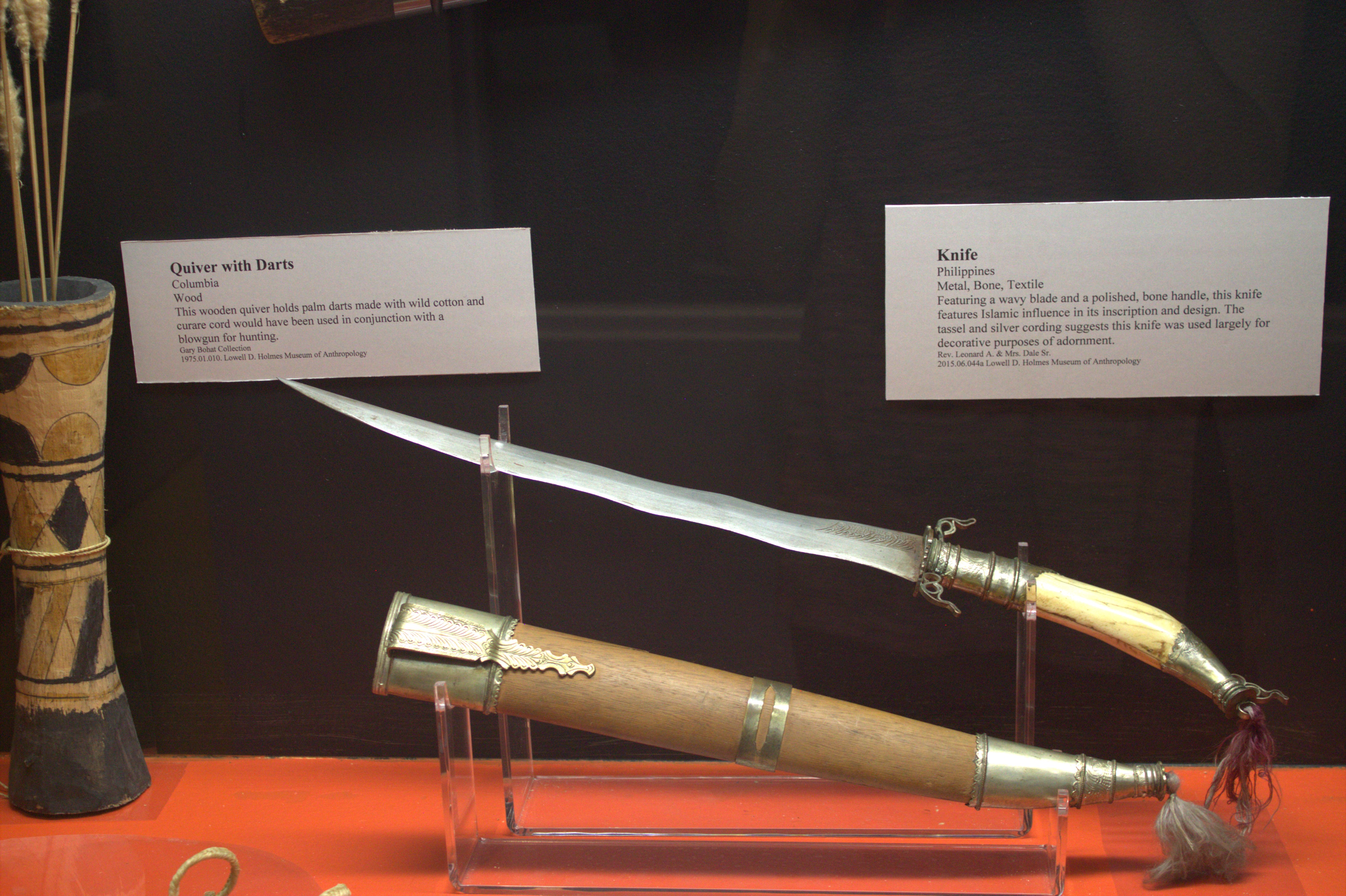 Display case with a black background and bright orange bottom with various objects on display