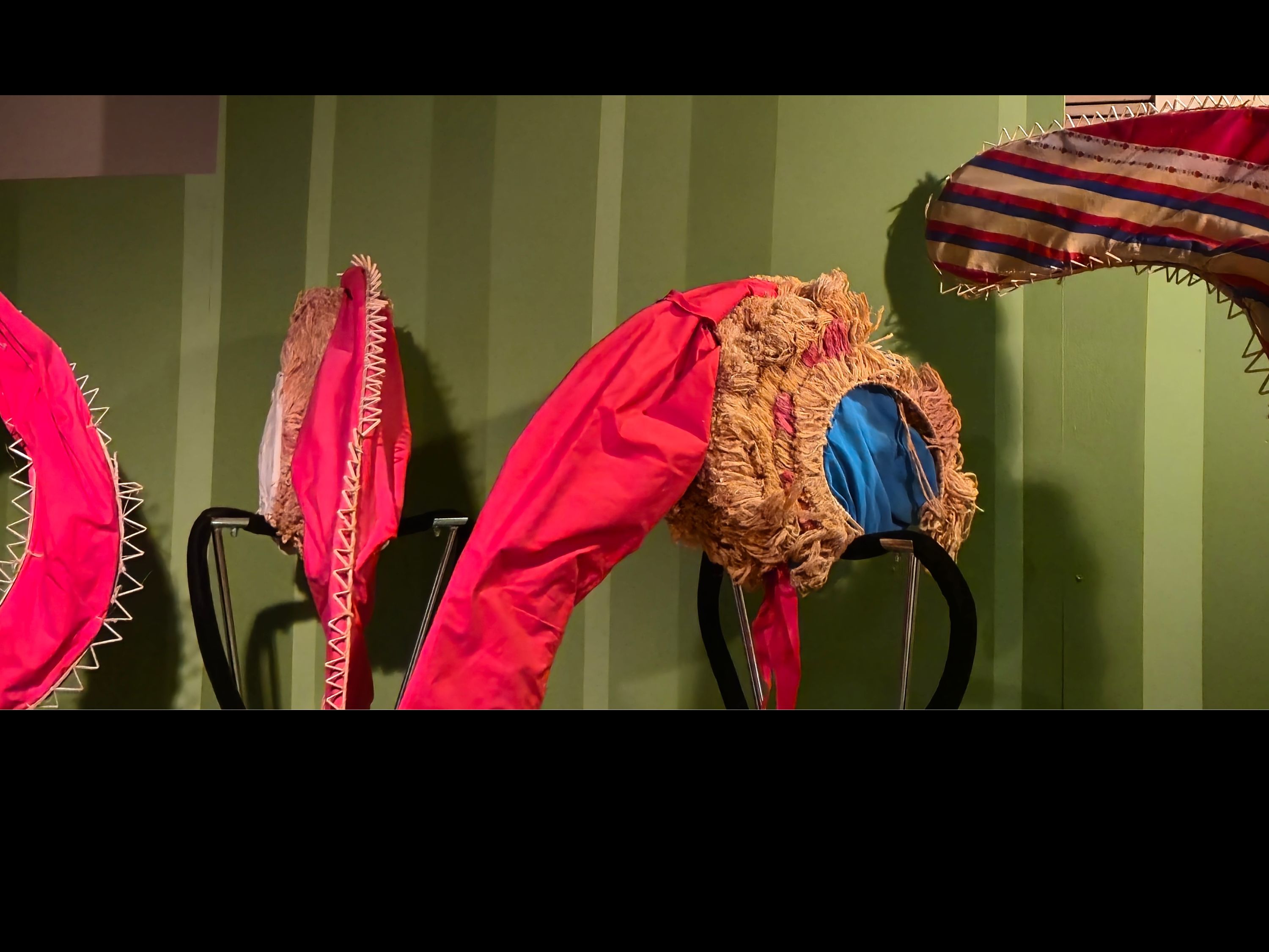 Open case with green background with mannequins with headdress on display.