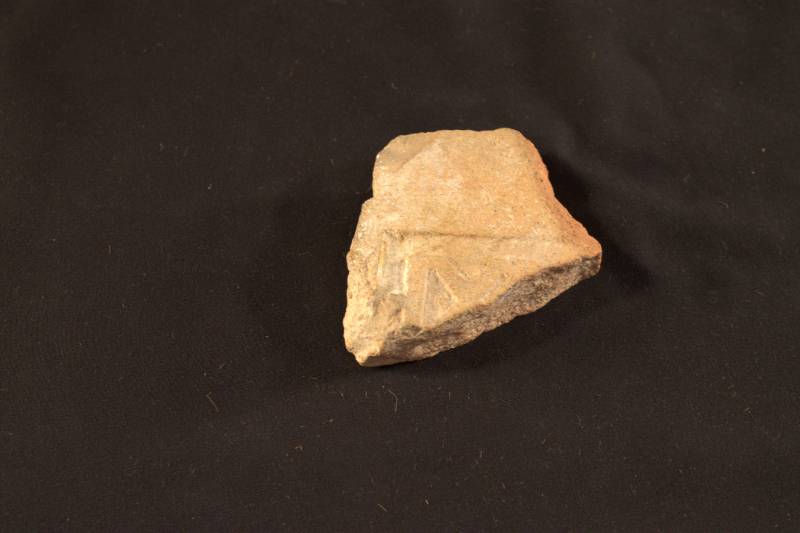 Tile The tile is light tan in color. It has some Greek writing or numerals carved into it.