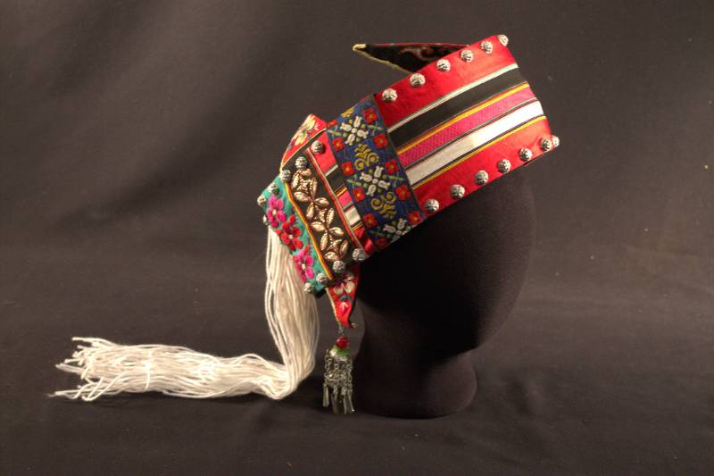 Bai Hat Hat is open in back, has silver beading and multi-colored flowers, yarn hanging from back, and built-in "earrings".