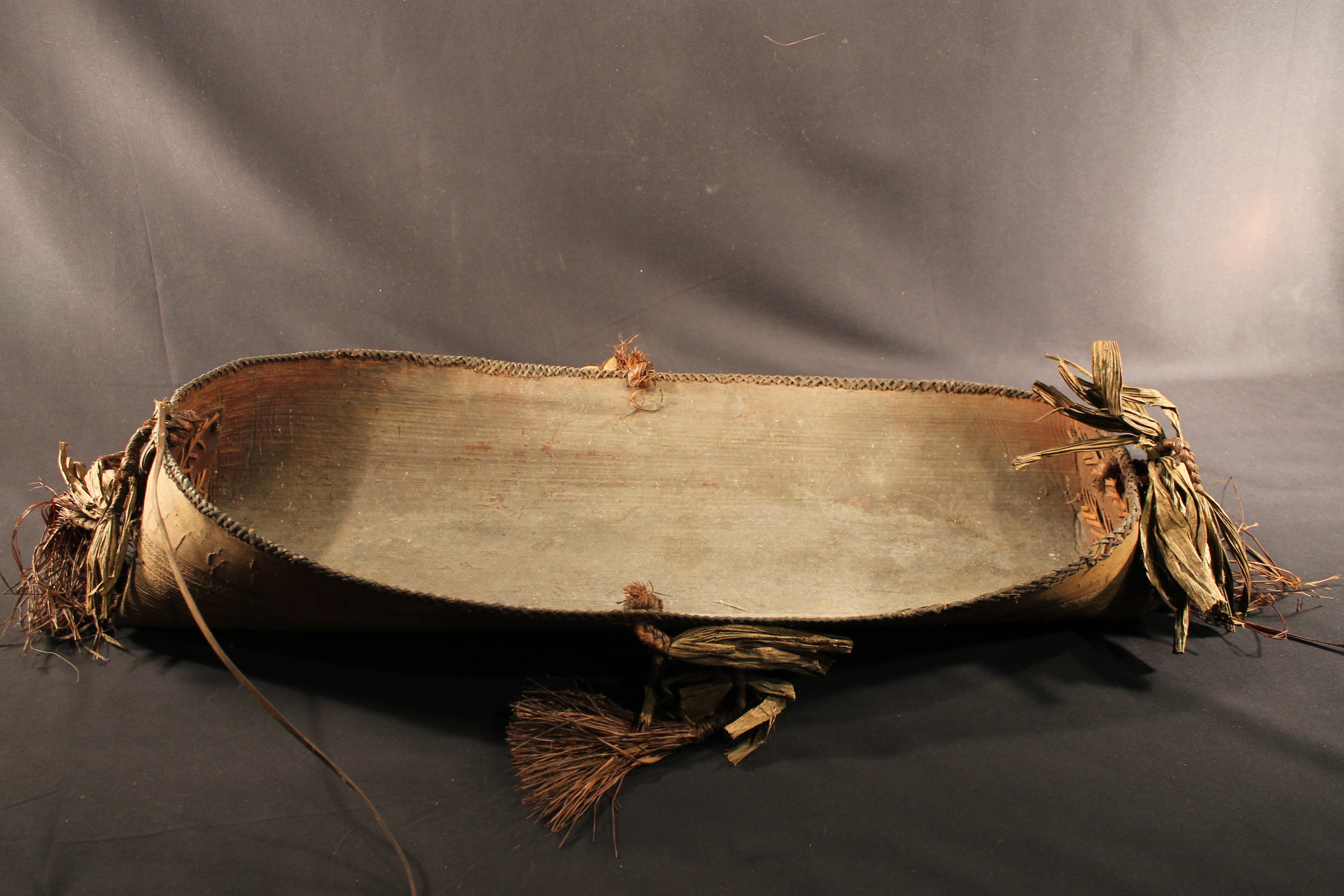 Brown wooden bowl with four tassels made of sleeves attached. 