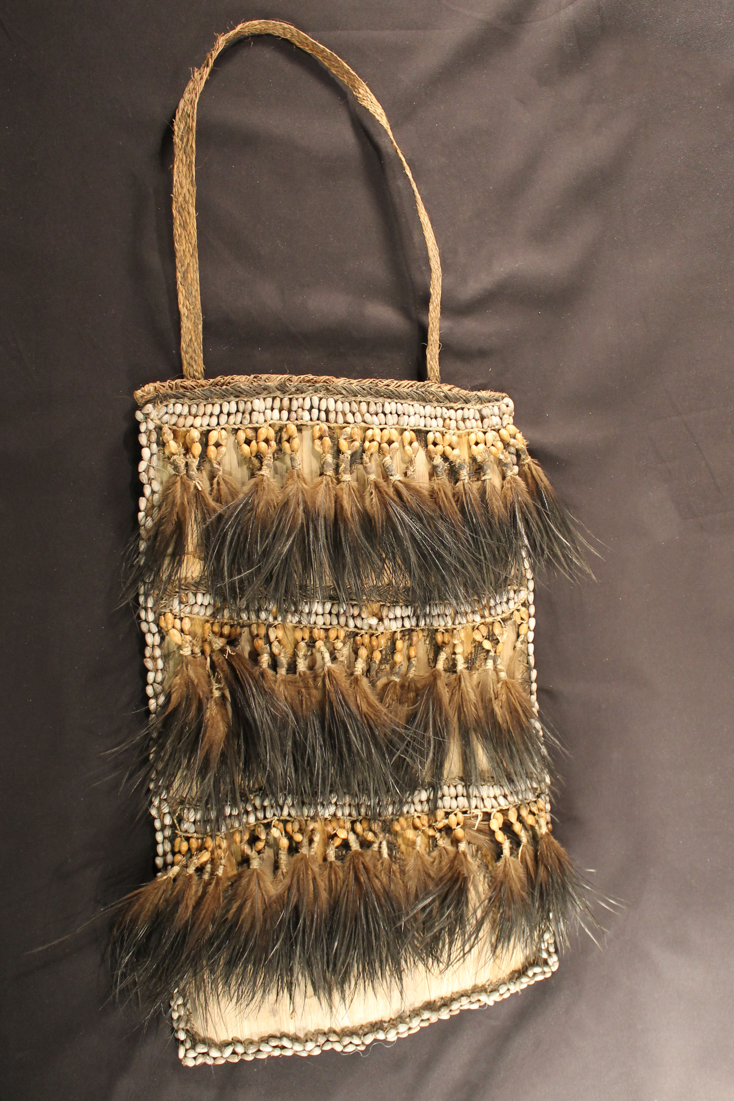 Woven bag with symbolic designs that has three-rows of seed beads and tassel feathers