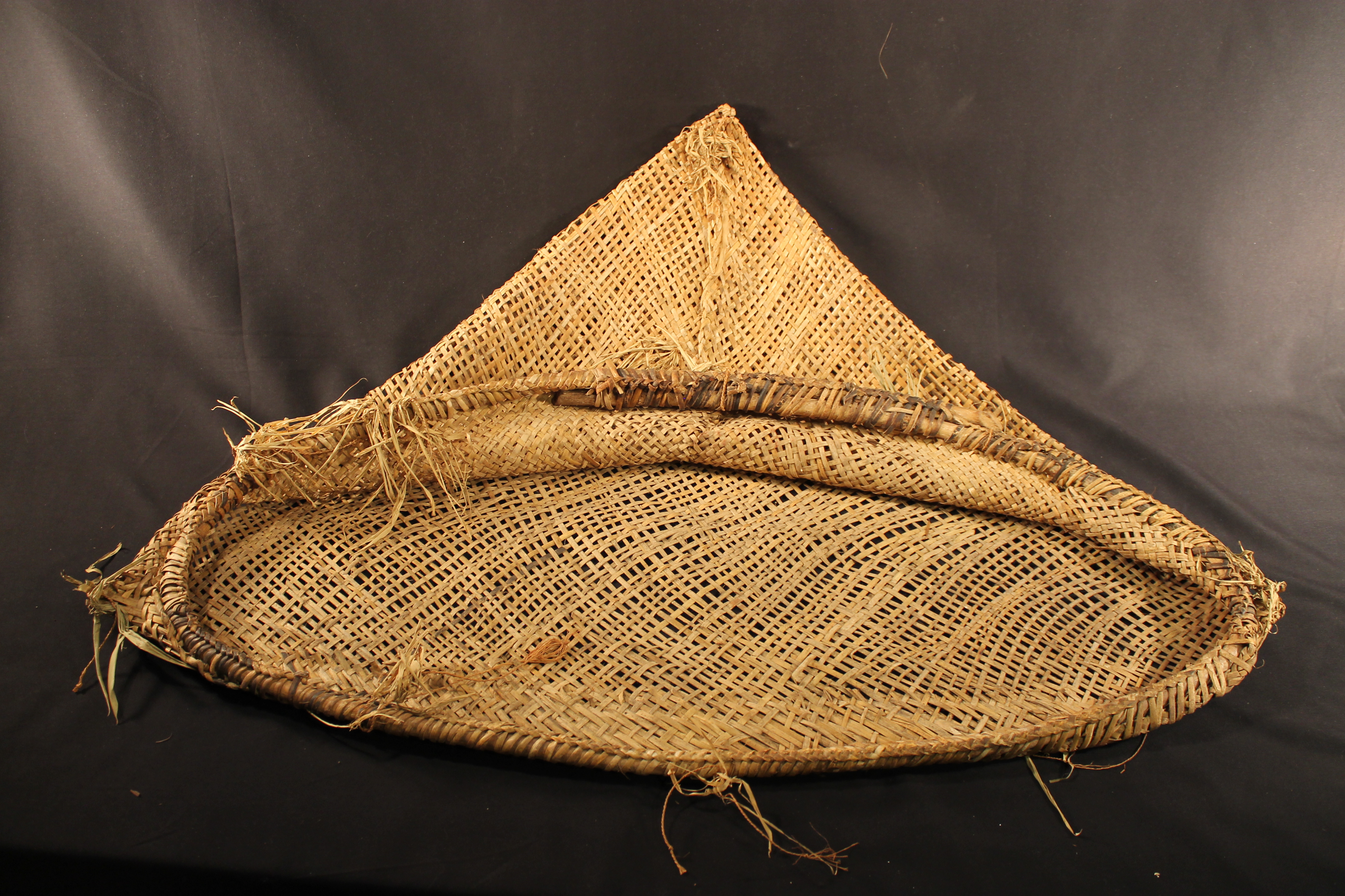 Woven net on rattan frame with vegetal tassels attached.