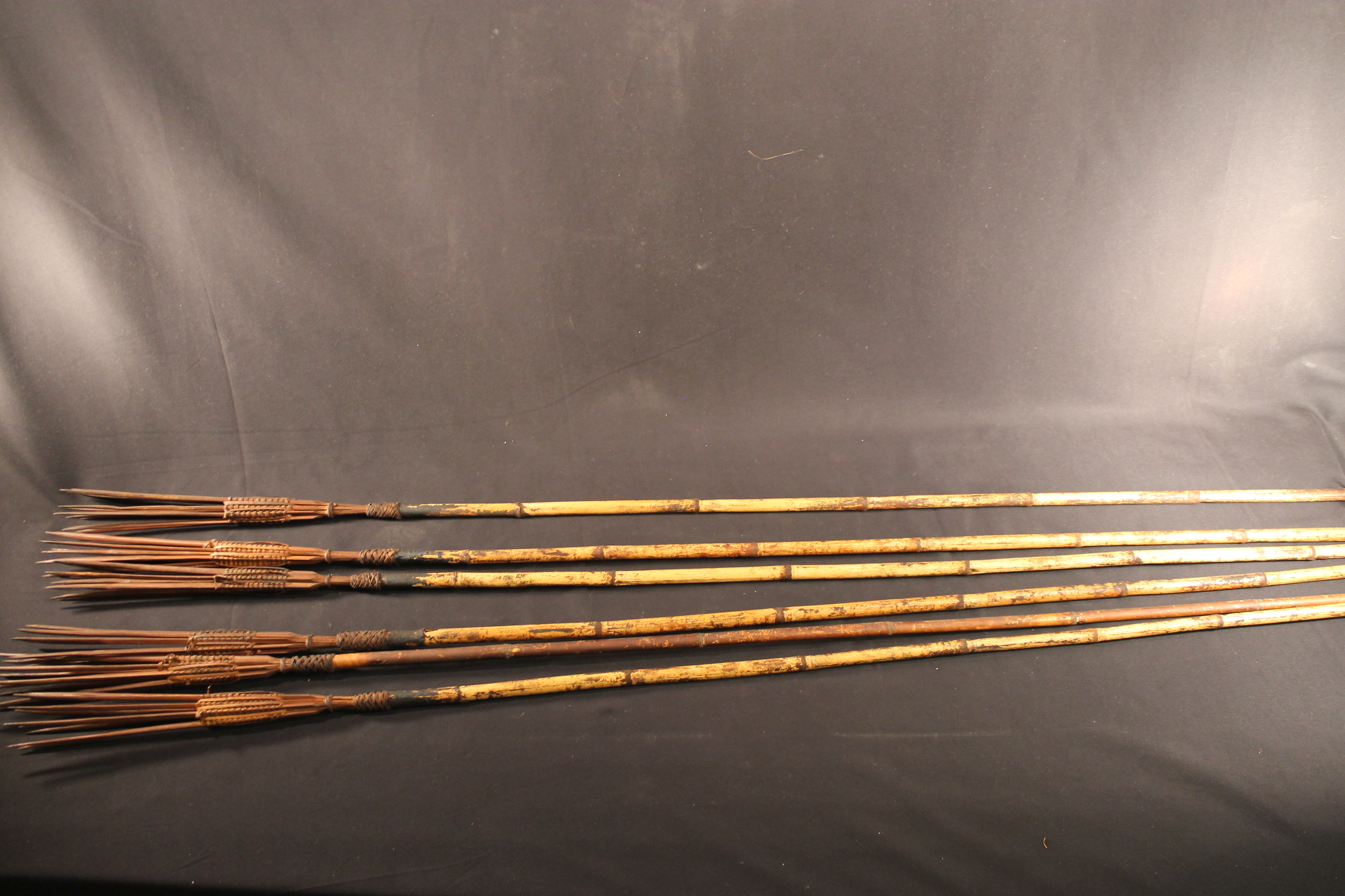 Cluster of six bamboo arrows tied together with a rattan strap.
