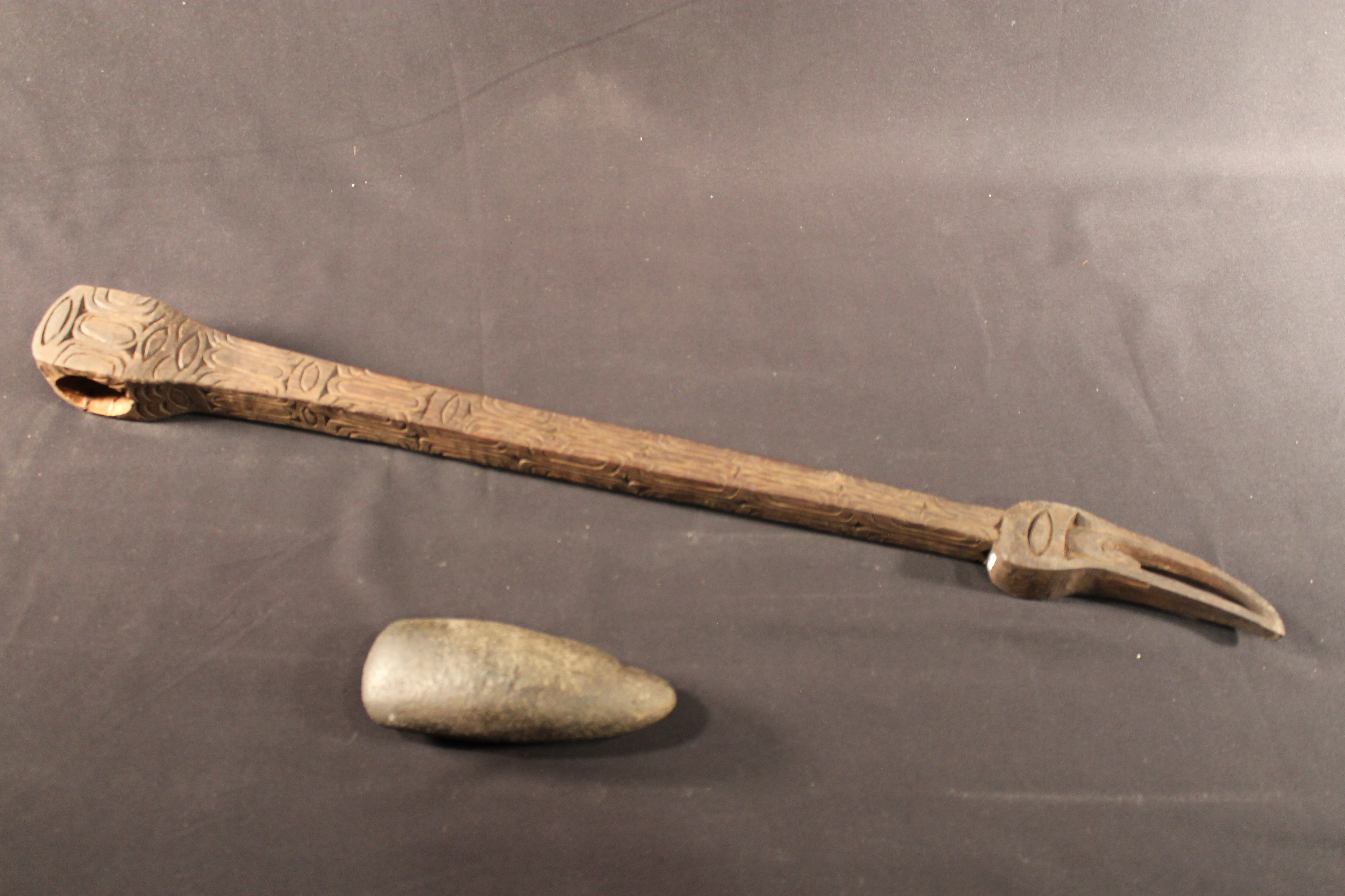  Stone blade ax with decorated handle. The handle has designs of frog legs, jungle fruit, and a hornbill bird’s head. 