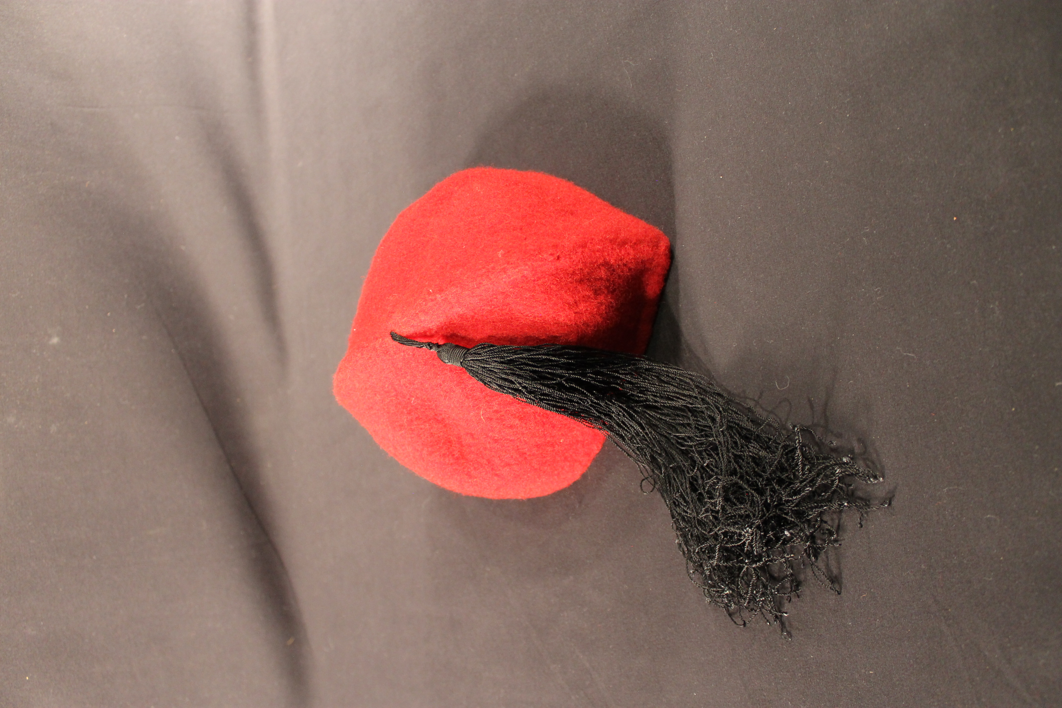 Red felt hat with a black tassel.