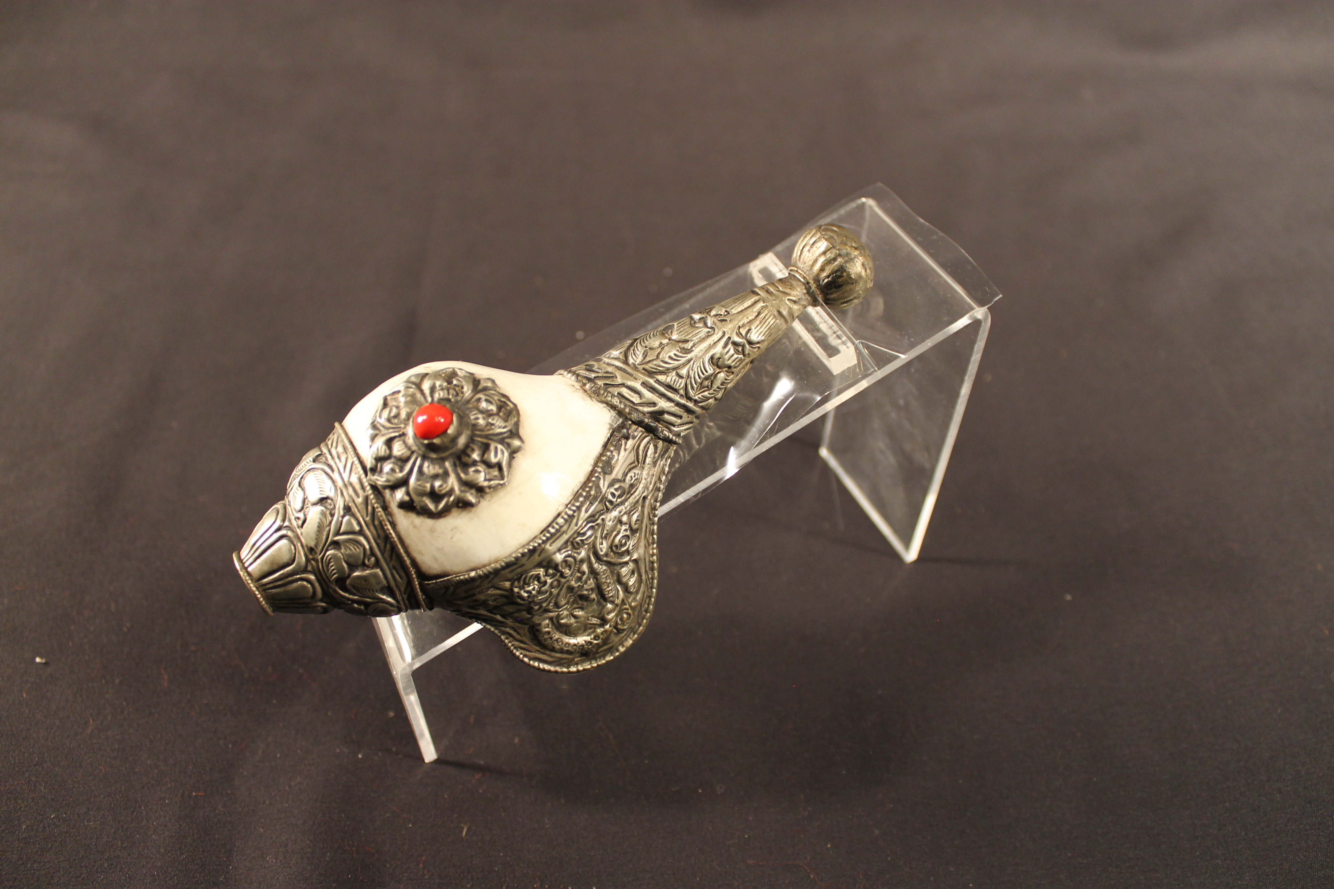 Horn is shell-shaped with a long silver handle with red stone on top.