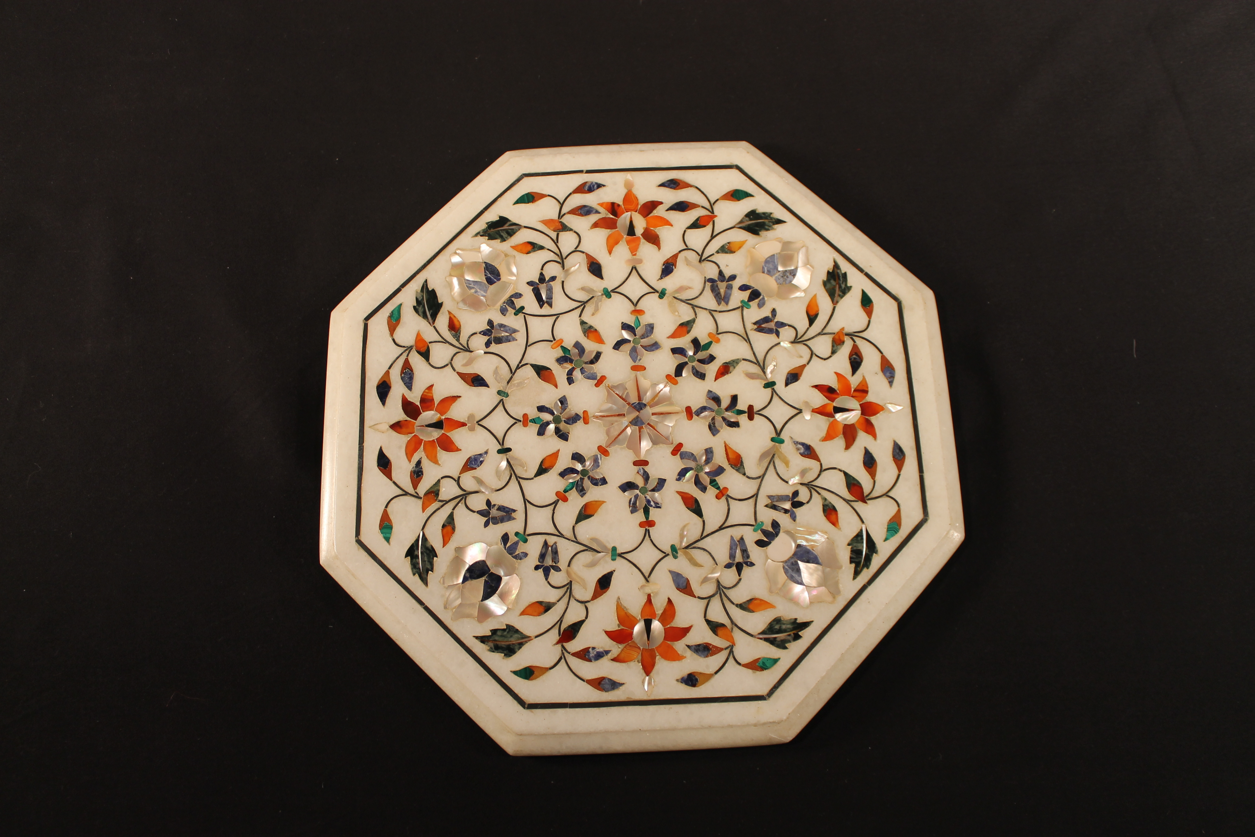 White marble octagon with multi-colored inlaid stones and mother of pearl.