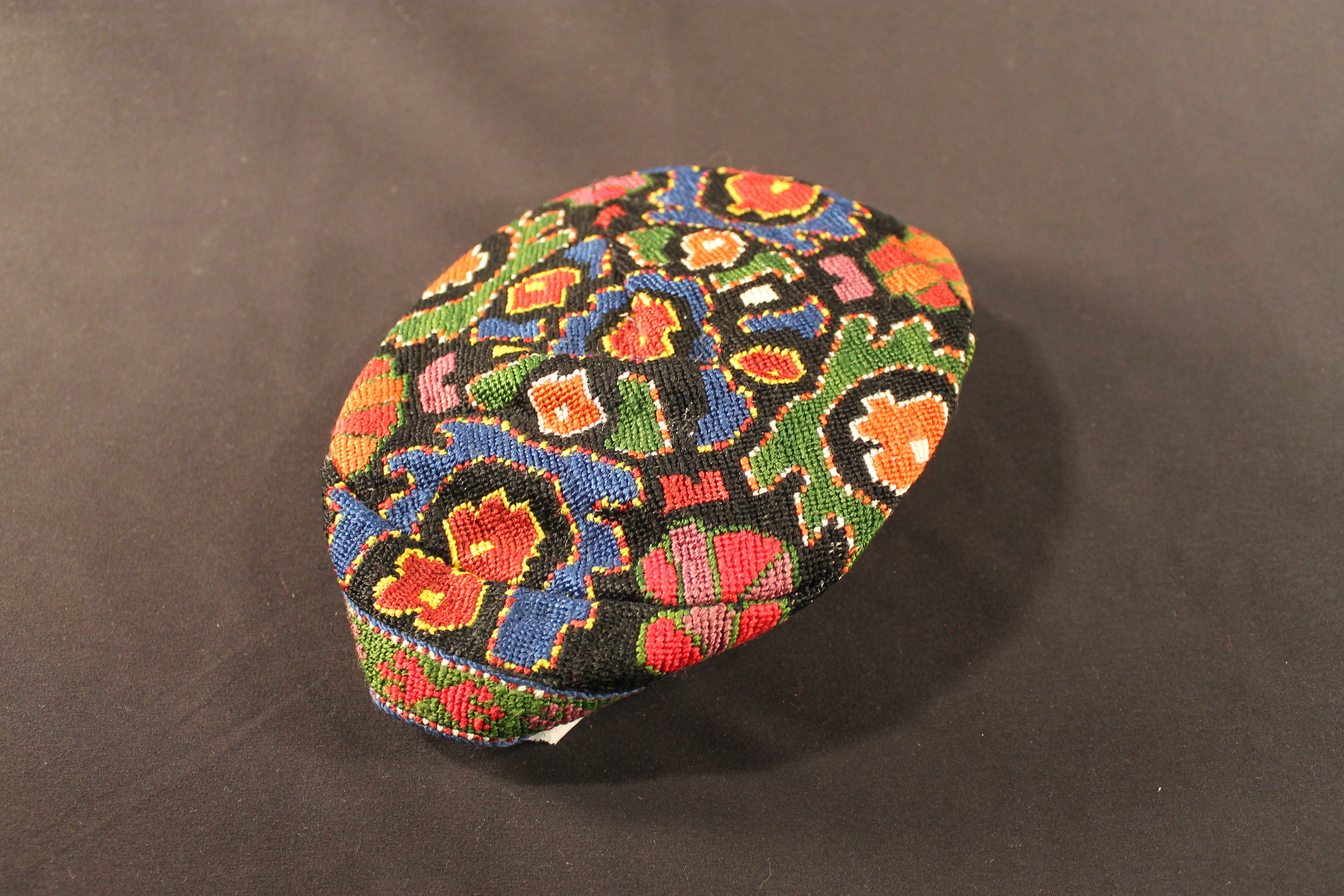 Black embroidered skull cap with colorful geometric designs. 