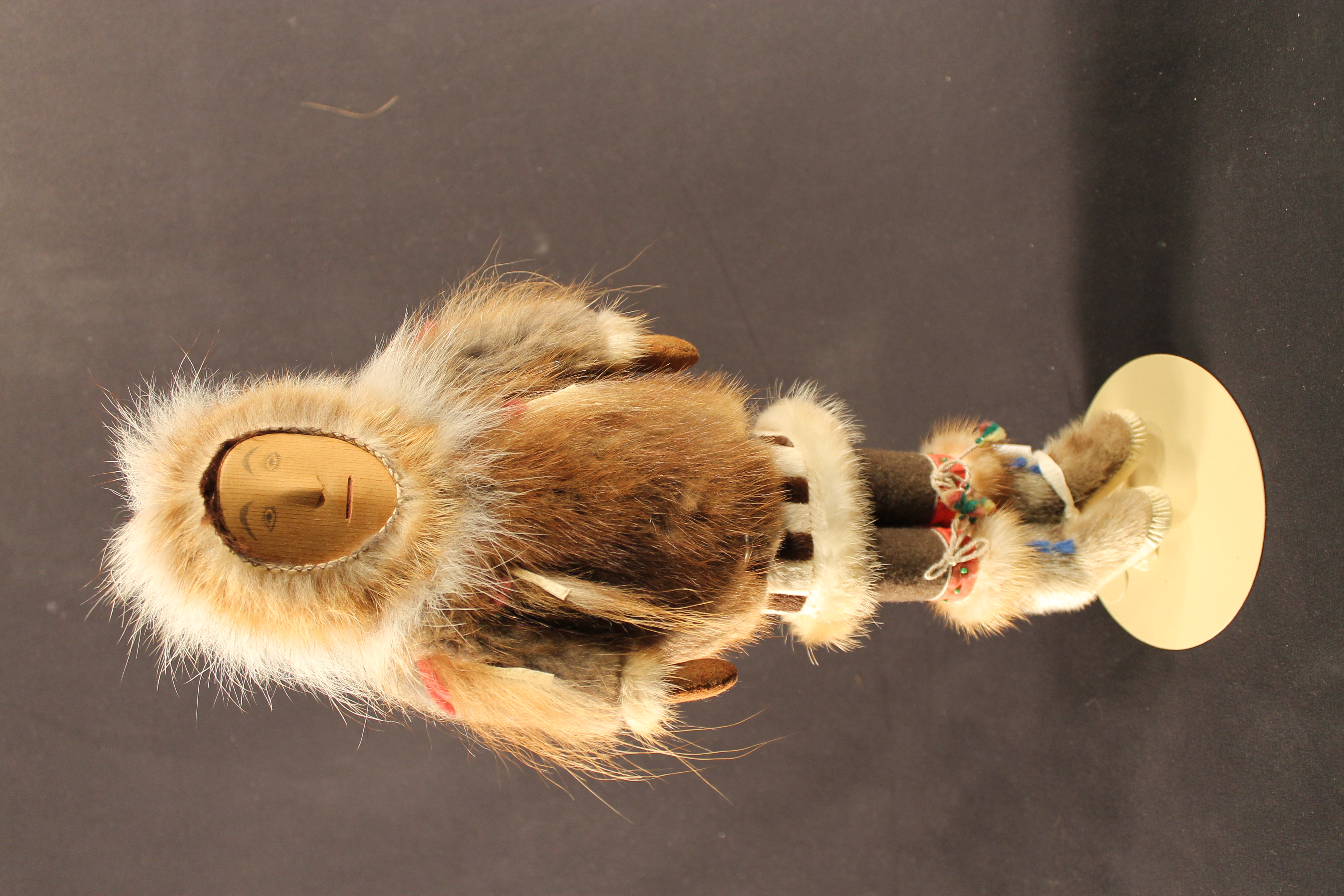 Doll with a wooden face, fur coat, and moccasins. 