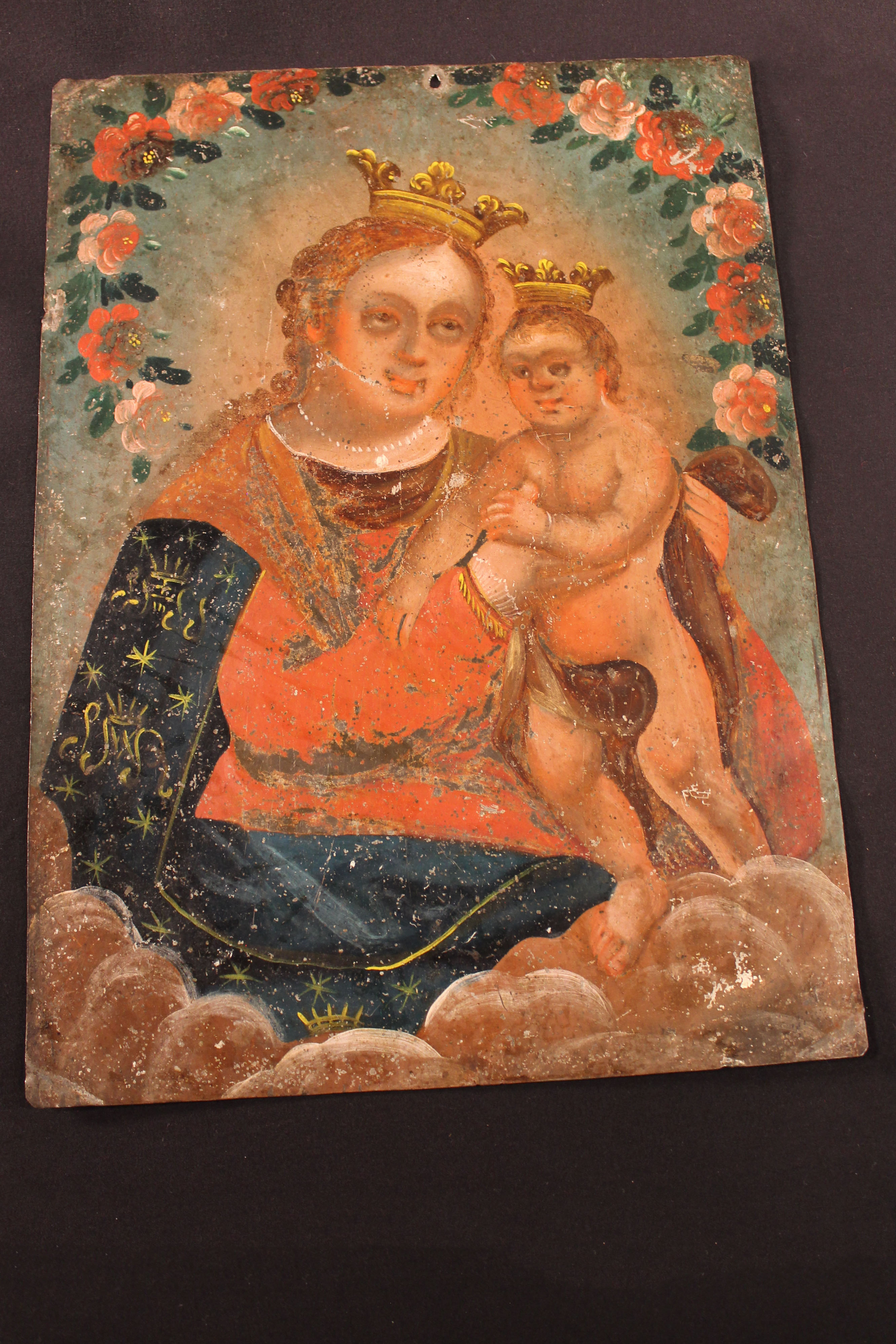 Retablo painting on tin of Virgin Mary holding a child; both wear a crown, roses circle at top of the painting.