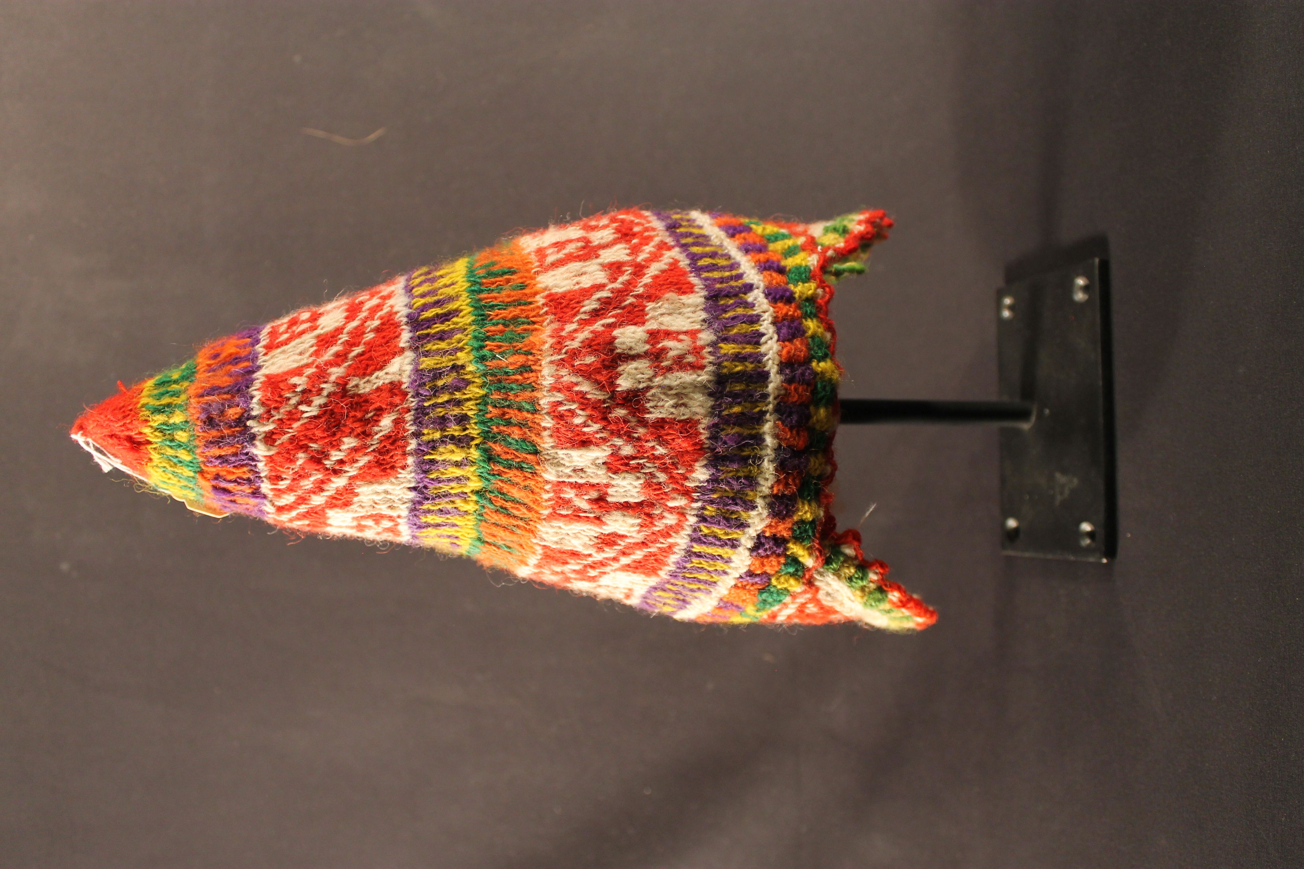 Cap made from a variety of bright-colored wool. Triangle shaped side earflaps.