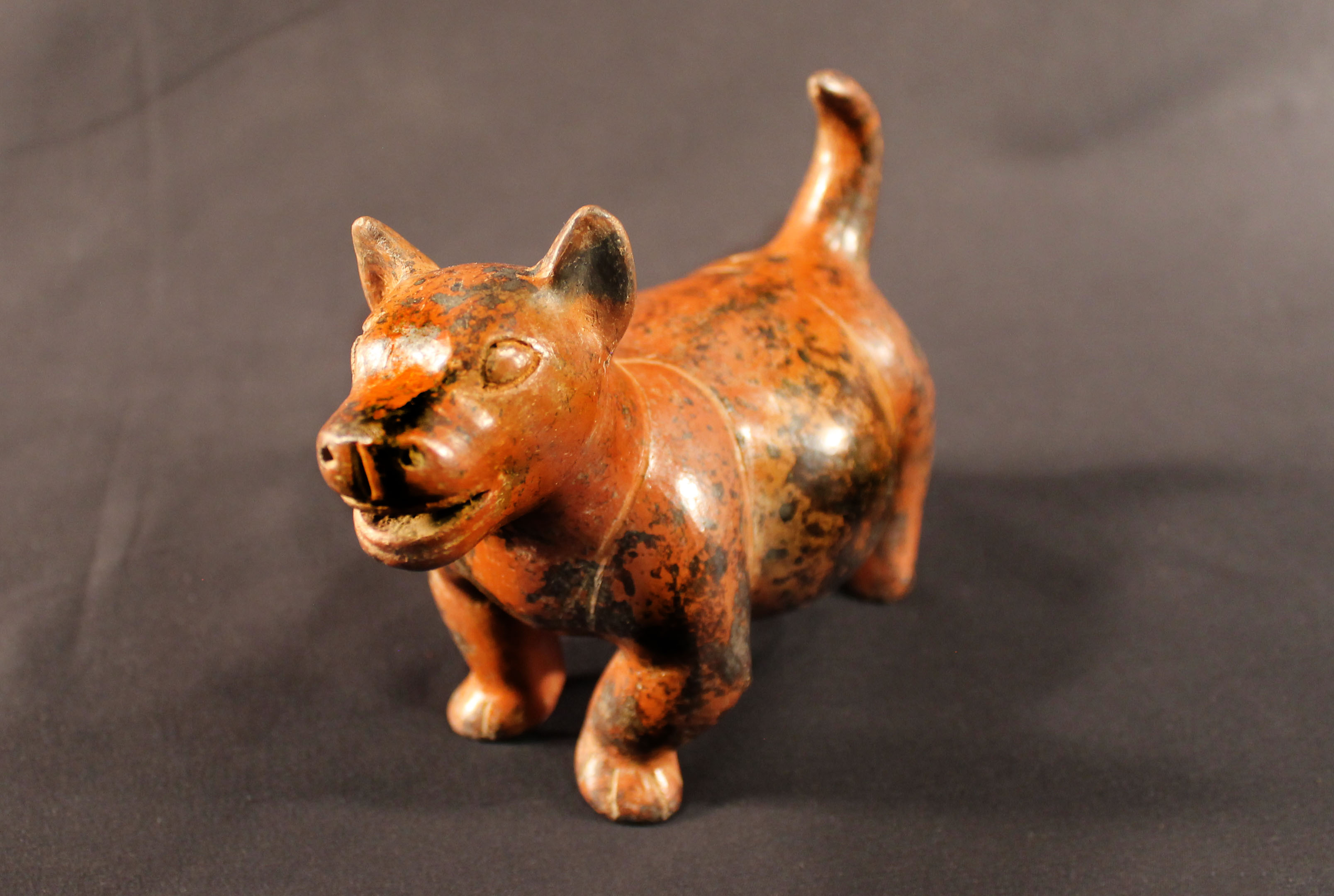 Red earthenware statute of a smiling chubby dog.