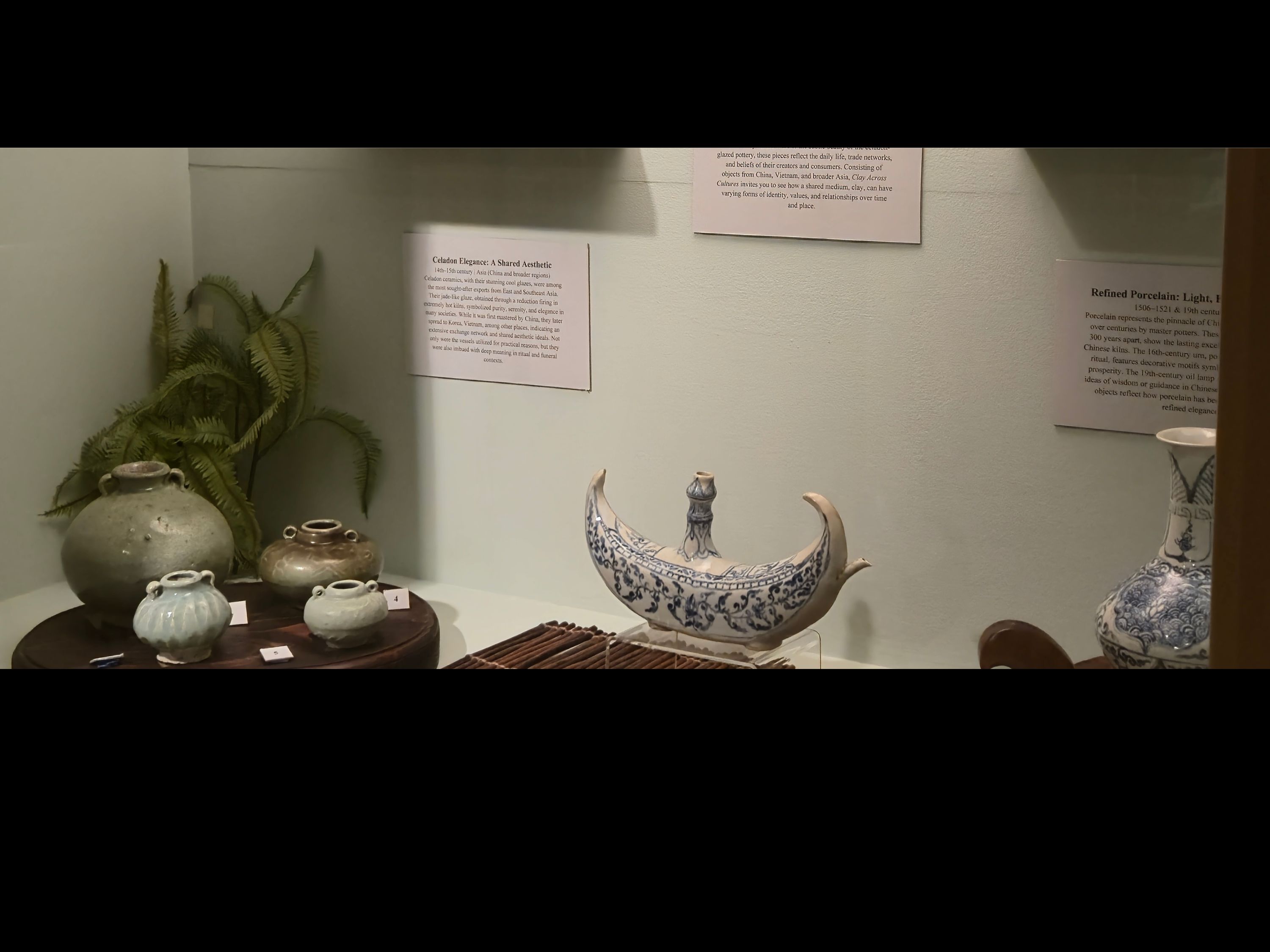 Display is both inside of a case and larger jar outside of case. The inside of the case is a light green with dark wood accents. Various jars and jarlets are on display inside the case.