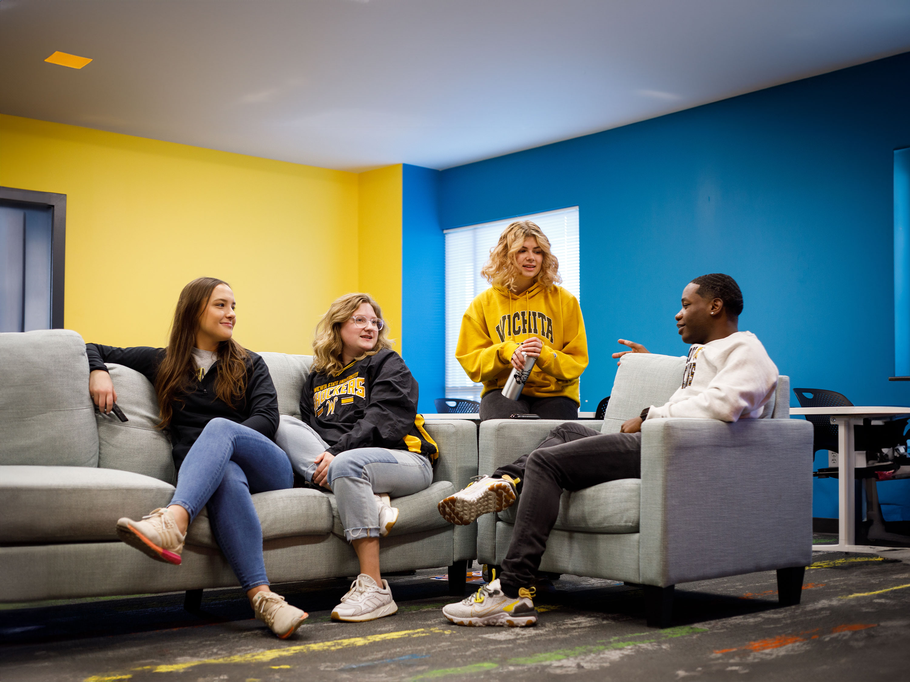 Four students talking to each other in a lounge area.