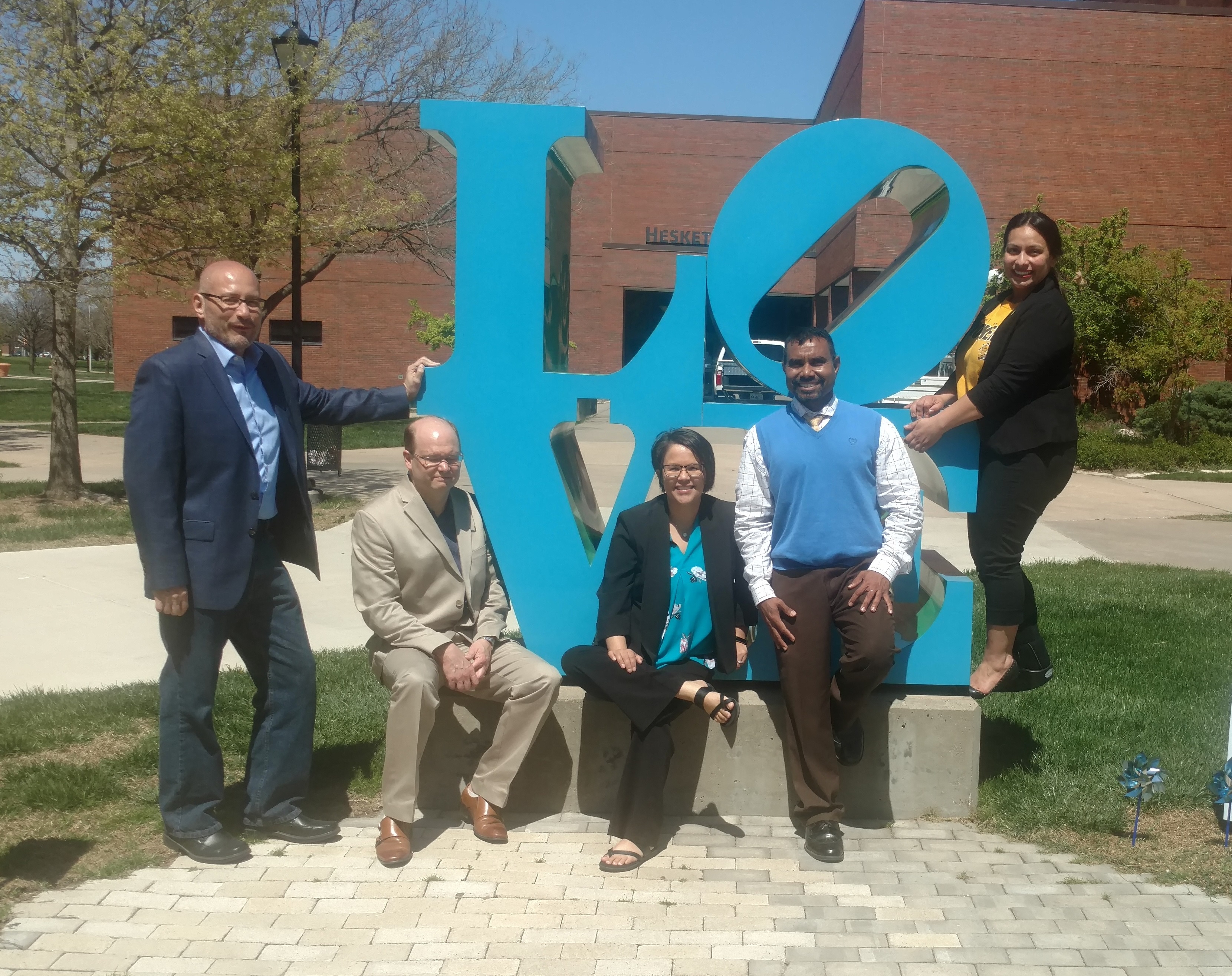 Photo of the TRIO magazine team posing around the campus LOVE sculpture.