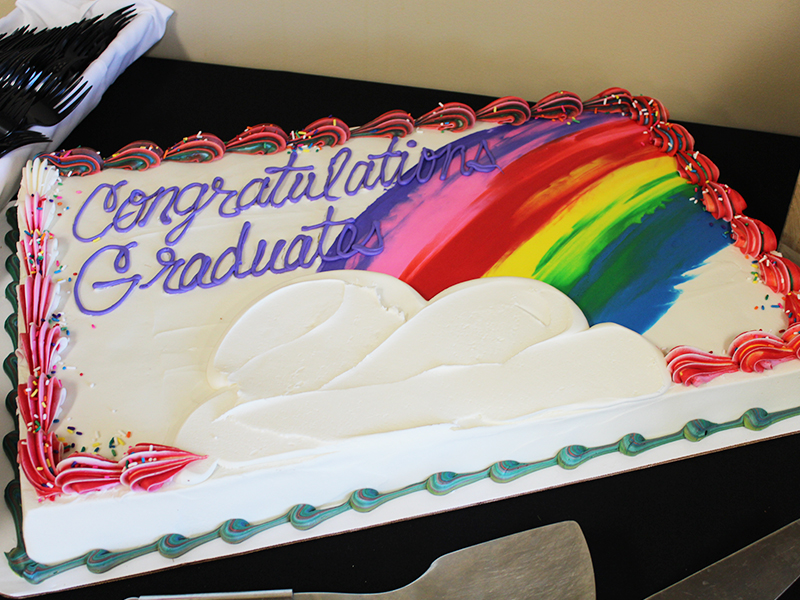 A graduation cake with rainbow colors streaked above a cloud.
