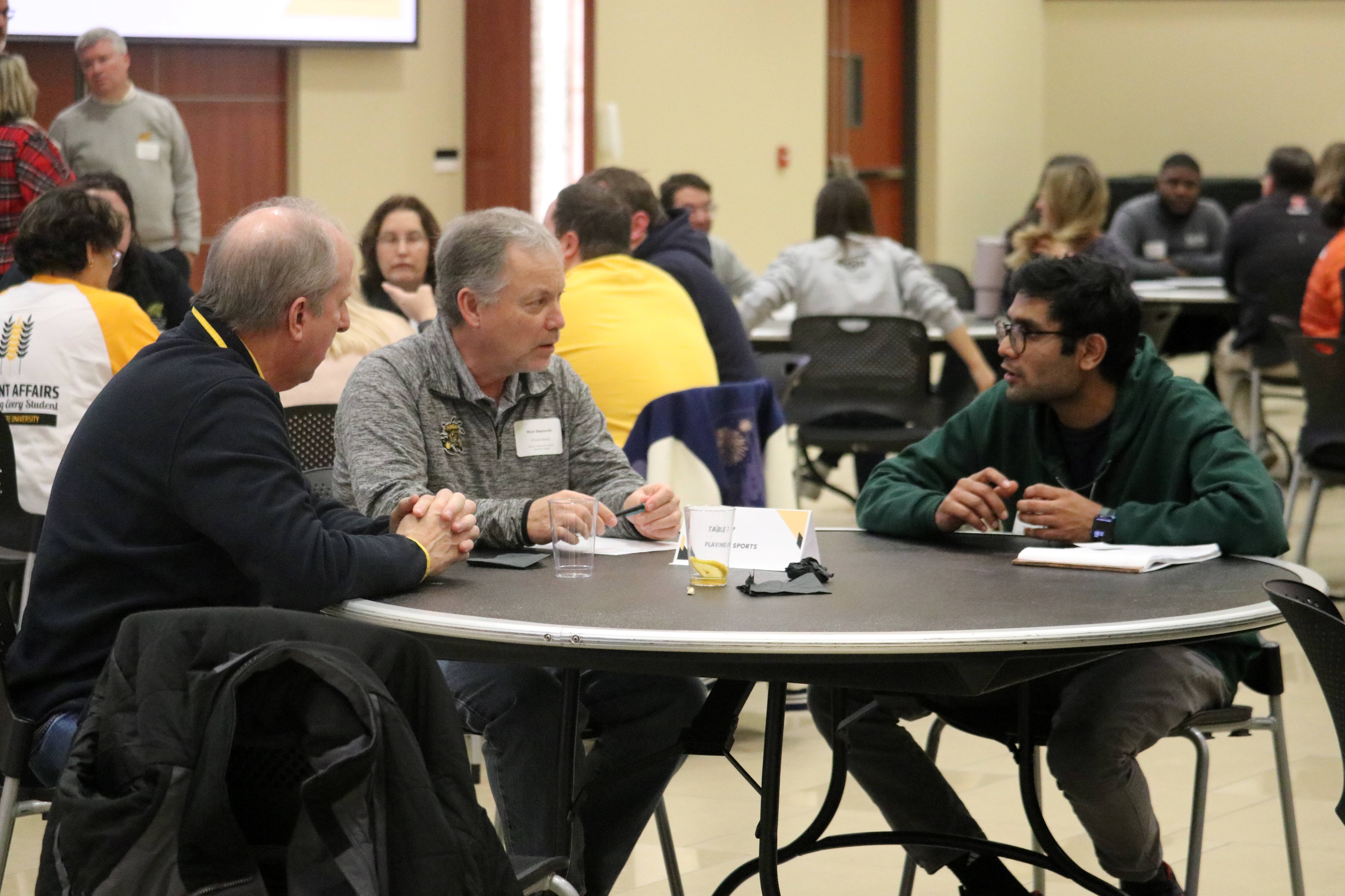men sitting around table and chatting