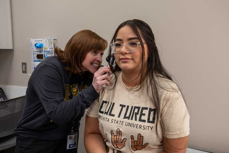 Student Health Services The provider is checking the patient's ears