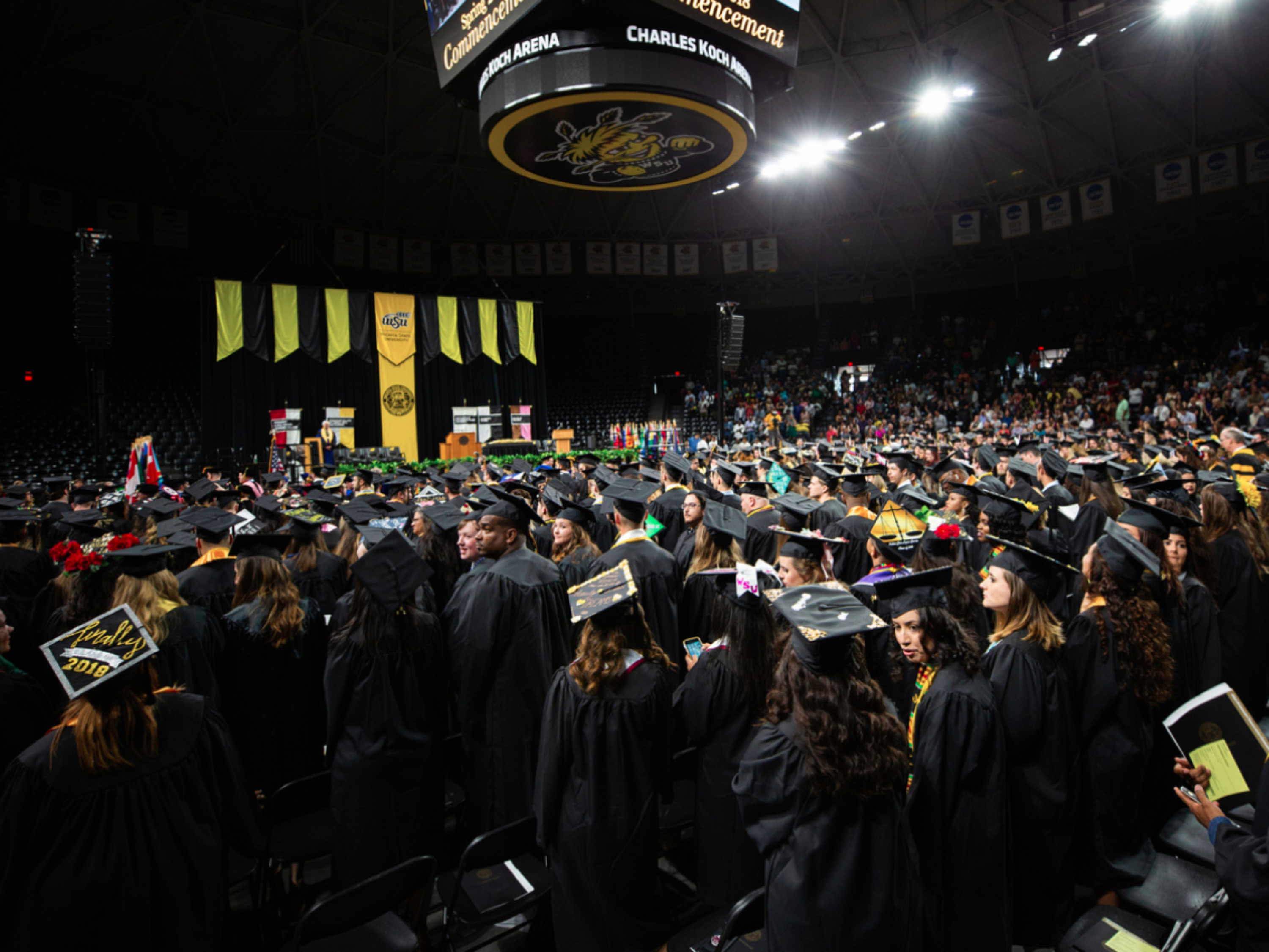 Photo of students in gowns and hats attending graduation. 