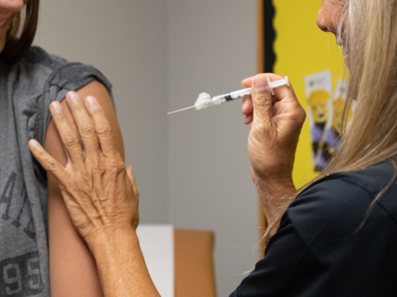Student receiving a shot injection from nurse.