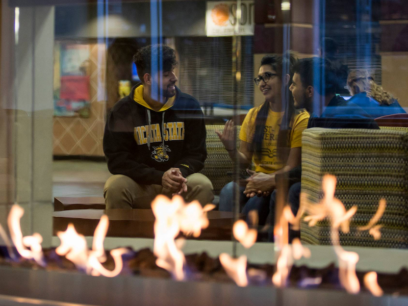 Photograph of three students visible through a window relaxing in the RSC. 