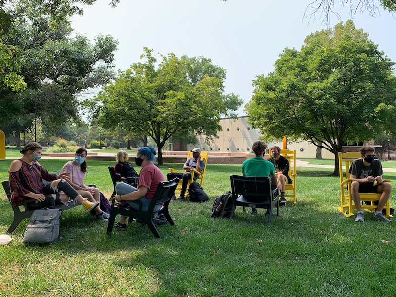Students gathered outside in rocking chairs during a First-Year Seminar. 
