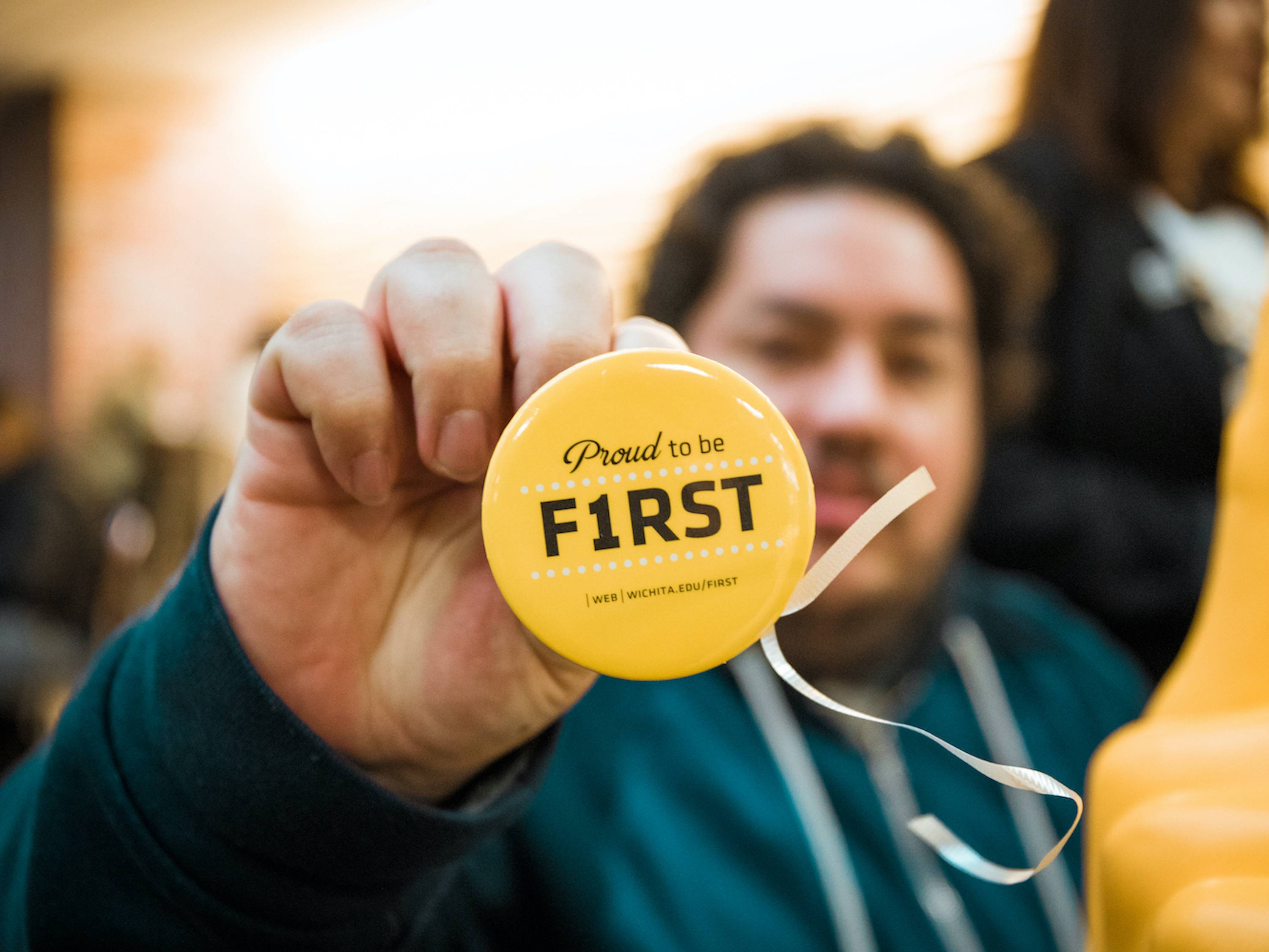 A First Year Student holds up his "Proud to be First" button. 