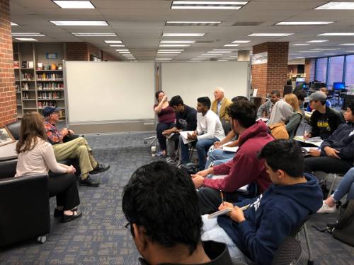 Photograph of students in the library listening to a lecture being given on the topic of World War II. 