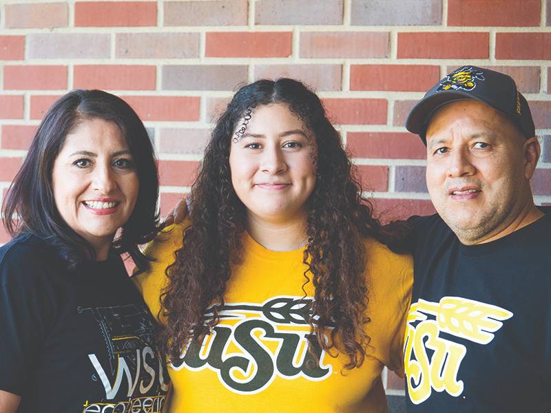 Two parents pose with their Shocker student