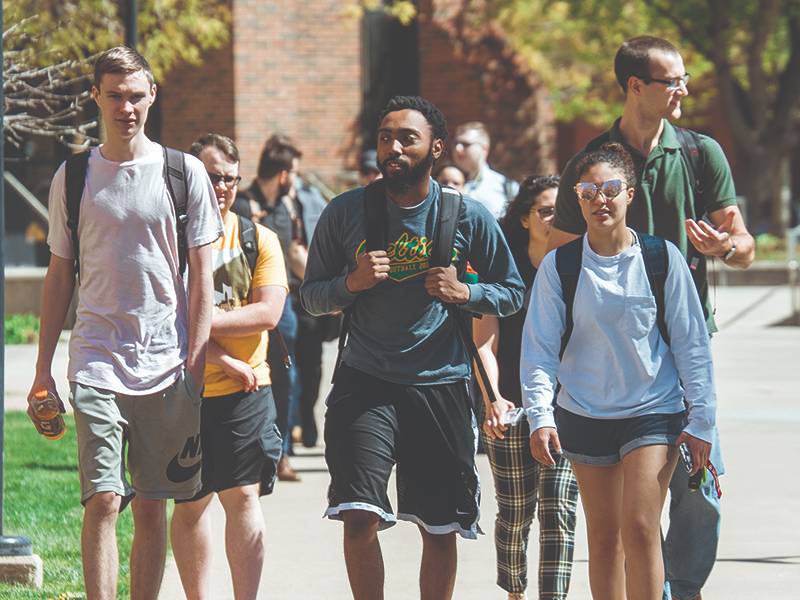 A group of friends walk together on campus to their next class