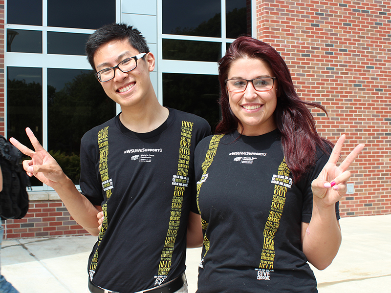 Two students pose in WeSupportU suspenders t-shirts