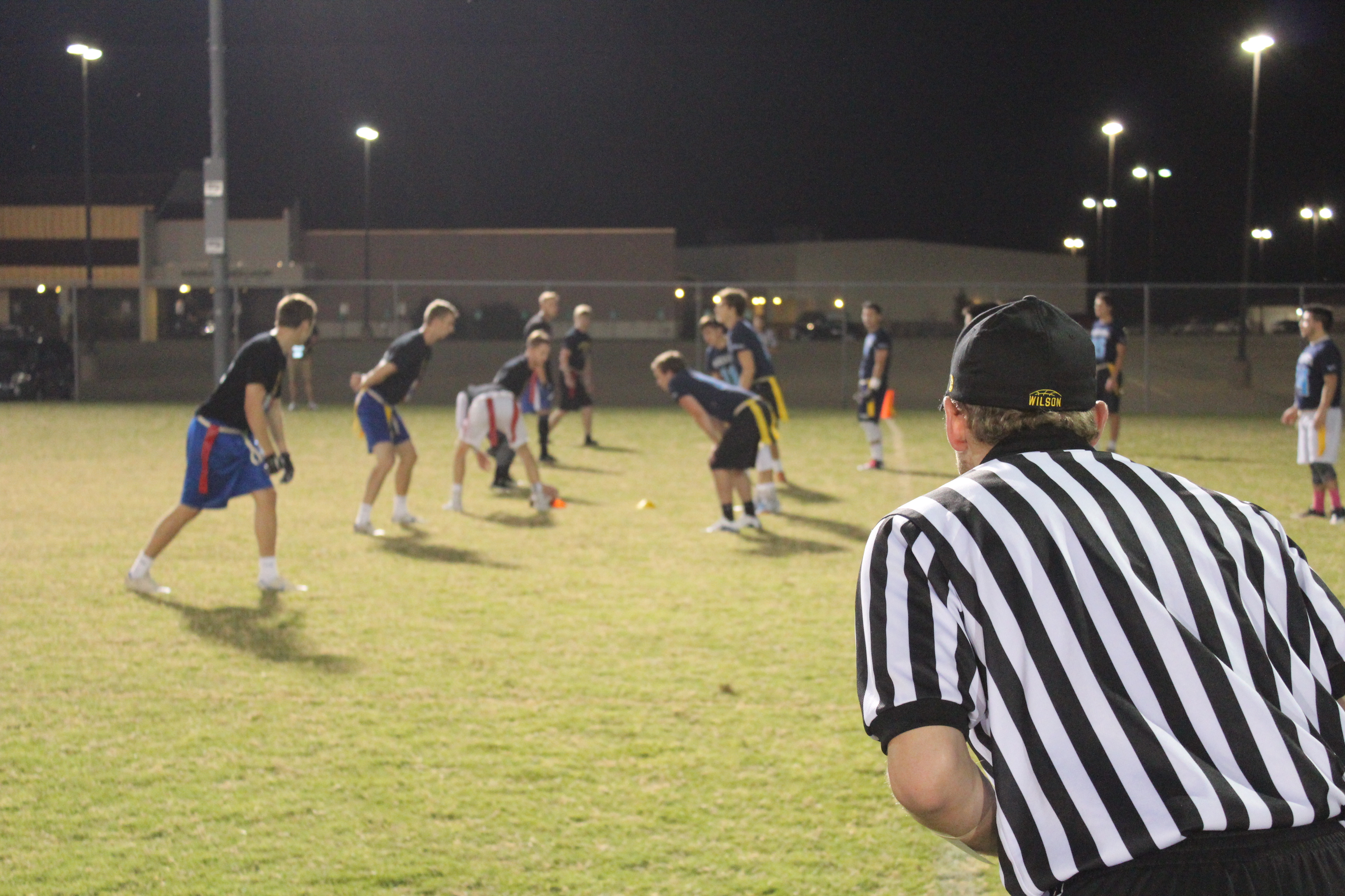 View from behind of a referee diligently overseeing a flag football game