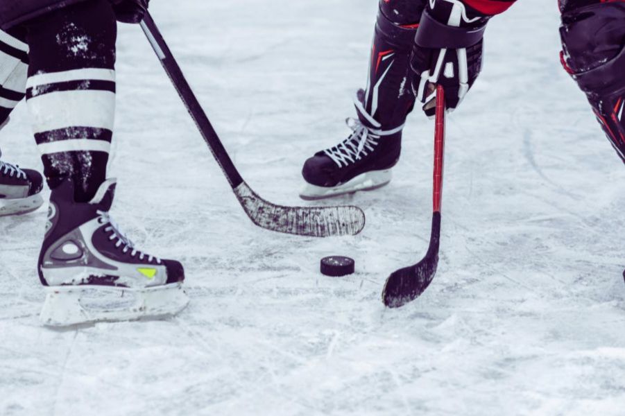 hockey players starting the game with a hockey puck between them