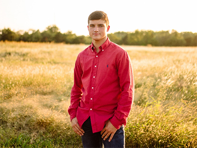 Photo of a student standing in a field at golden hour.