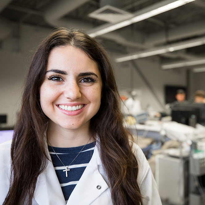 Photo of woman in a lab coat smiling at the camera